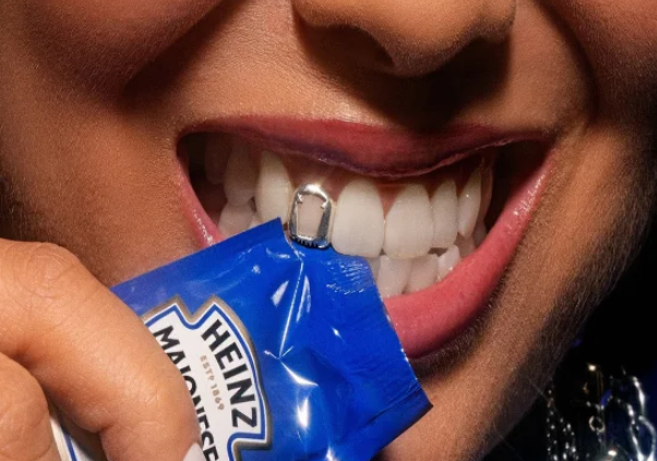Pessoa tentando rasgar sachê de molho com os dentes em praça de alimentação
